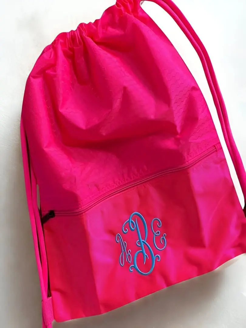 Pink drawstring bag with blue initials.